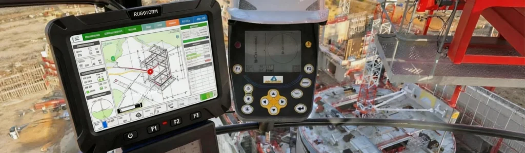 A rugged industrial monitor mounted inside a crane operator's cabin, displaying complex 3D construction site blueprints and real-time load data overlooking an active building site.