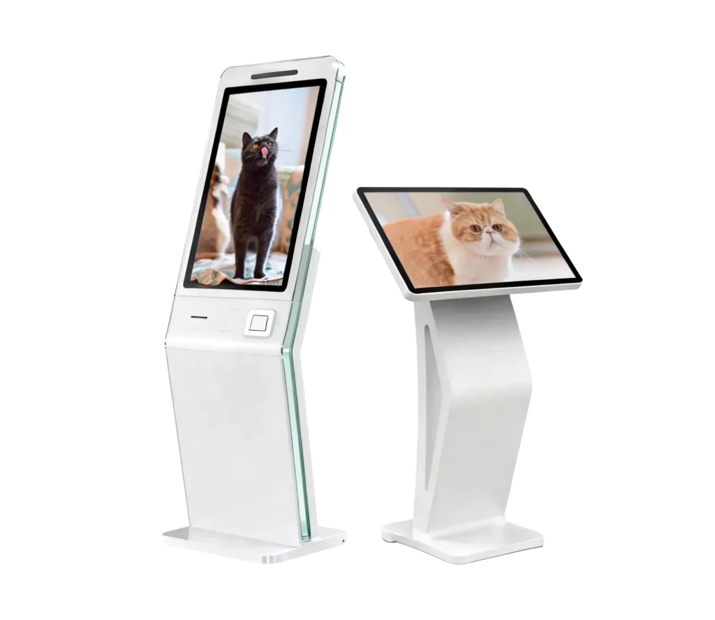 Two modern white digital signage kiosks on a gray background; one is a tall vertical totem displaying a black cat, and the other is a slanted touch-screen pedestal displaying a fluffy ginger and white cat.