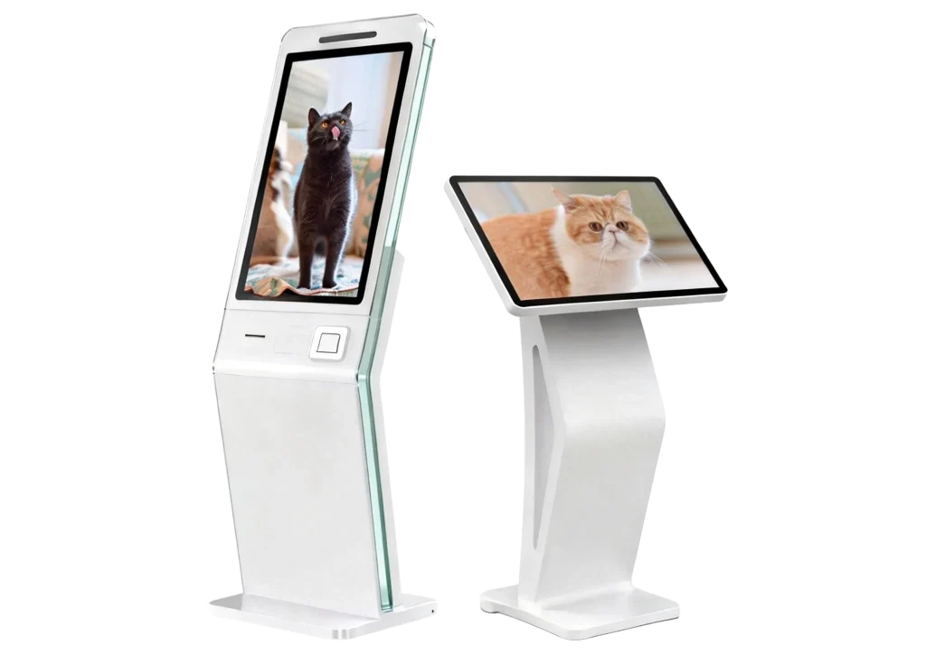 Two modern white digital signage kiosks on a gray background; one is a tall vertical totem displaying a black cat, and the other is a slanted touch-screen pedestal displaying a fluffy ginger and white cat.