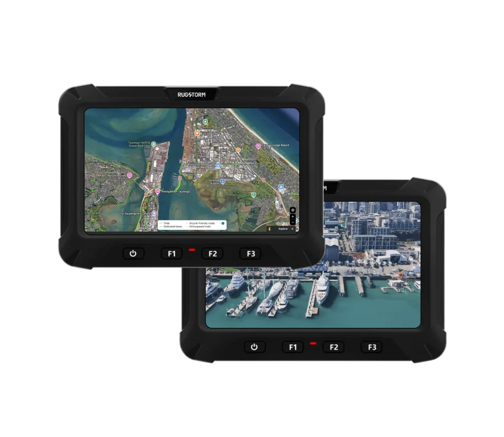 Two Rugstorm vehicle mounted display -VD70 displayed against a grey background; the front screen shows a satellite GPS map of a coastal port, and the back screen shows an aerial view of a marina with yachts.